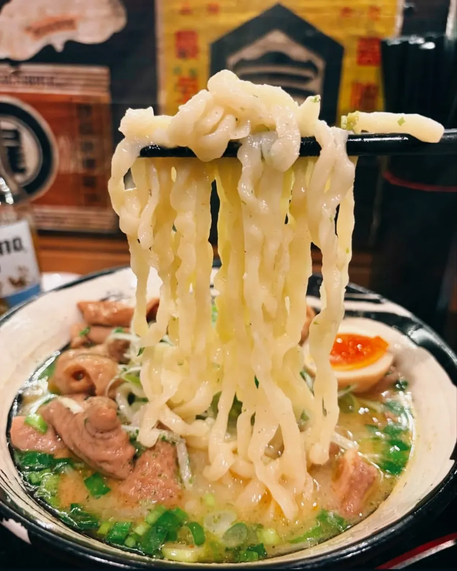 箸で持ち上げた中太の縮れた麺